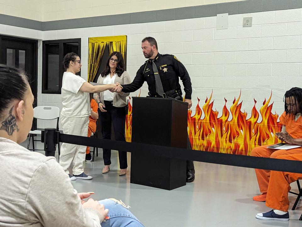 Sandusky County Sheriff's Office I.G.N.I.T.E. Program Coordinator Caren Nemitz gets ready to hand a diploma to Krista Strub, as Sheriff Chris Hilton shakes Strub's hand. Strub was one of the speakers at the graduation ceremony on March 20, 2024.