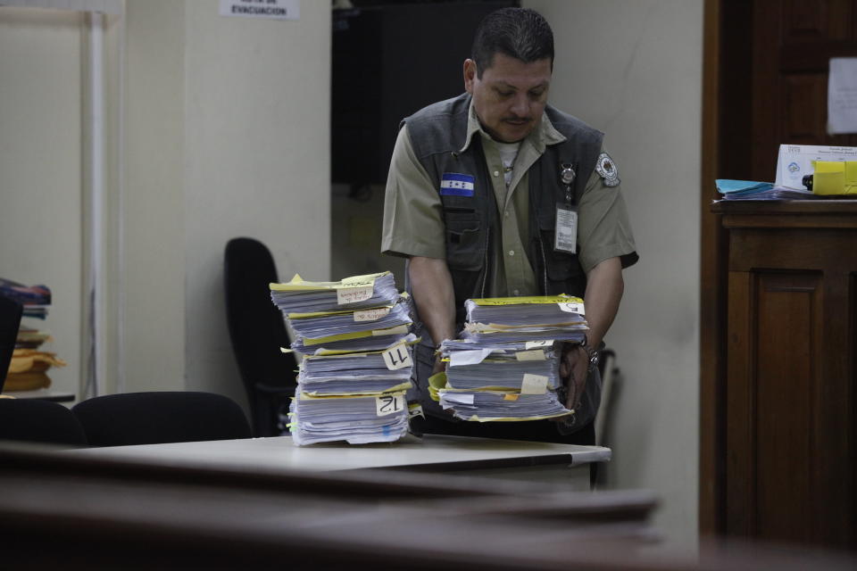 The court bailiff stacks the paperwork in the trail of the men accused in the killing prize-winning Honduran indigenous and environmental rights activist Berta Caceres, in Tegucigalpa, Honduras, Monday, Sept. 17, 2018. Honduras' supreme court has indefinitely suspended the start of the trial of eight men accused in the 2016 killing of Caceres, citing five related filings pending at the criminal appeals court that have to be resolved. (AP Photo/Fernando Antonio)