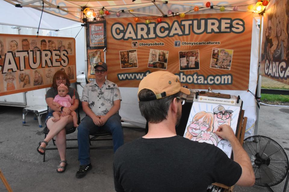 A family poses for a caricature at the Williamson County Fair in Franklin, Tenn. Monday, Aug. 8, 2022.