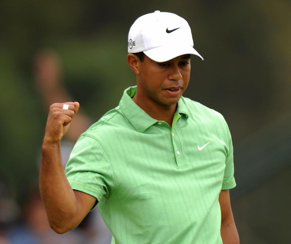 tiger woods flexing with his right arm as he celebrates a golf shot