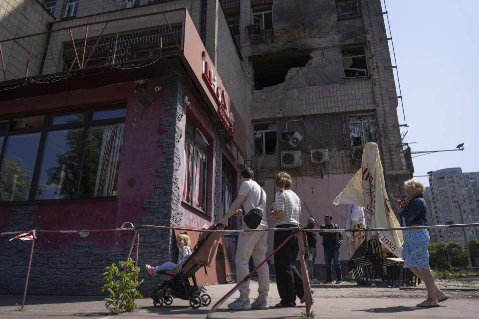 People look at an apartment building damaged by a drone during a night attack in Kyiv, Ukraine, Sunday, May 28, 2023. Ukraine's capital was subjected to the largest drone attack since the start of Russia's war, local officials said, as Kyiv prepared to mark the anniversary of its founding on Sunday. (AP Photo/Vasilisa Stepanenko)