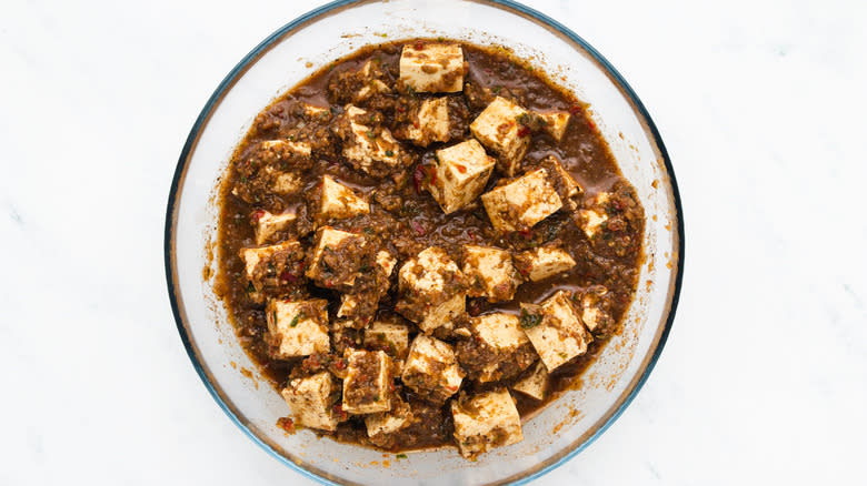 Tofu and jerk marinade in mixing bowl