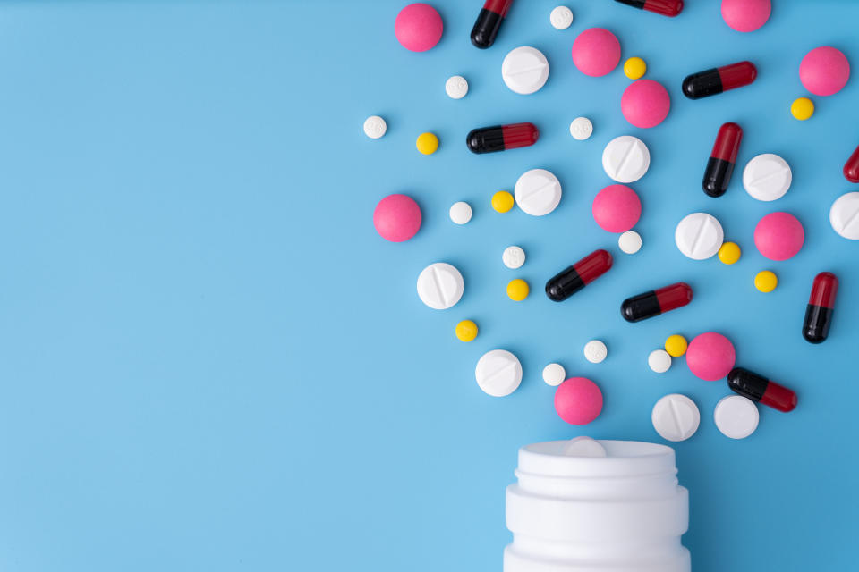 High Angle View Of Pills Spilling Form Bottle On Blue Background