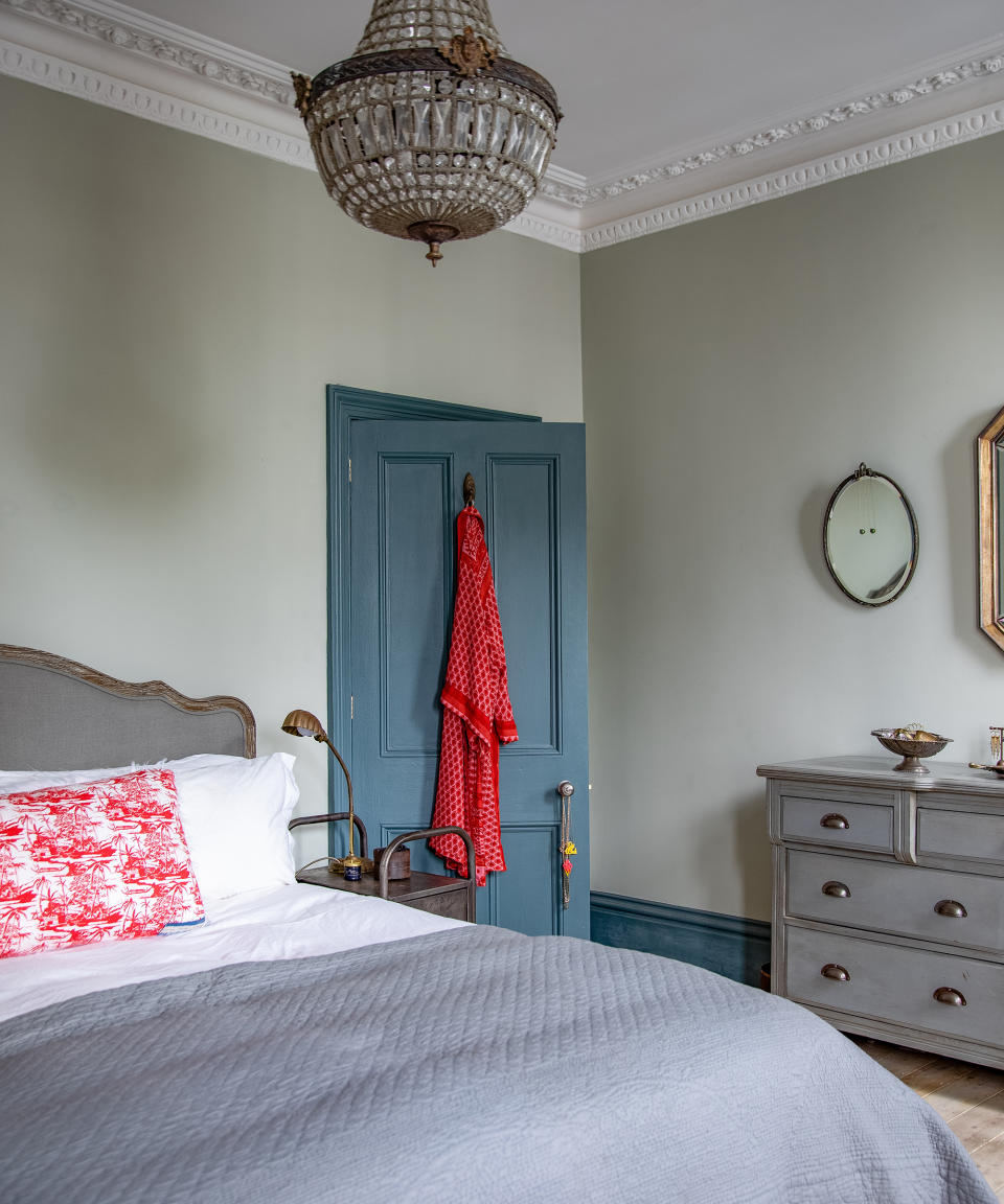View in blue bedroom towards a blue painted door and chest of drawers