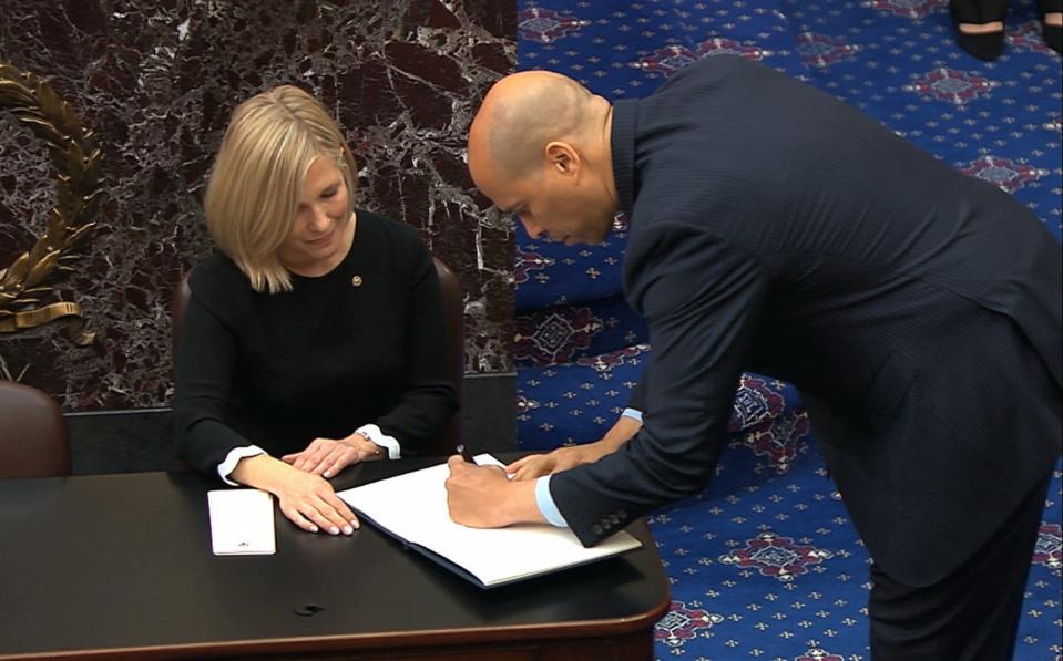 <span class="caption">Sen. Cory Booker, D-N.J., signs the oath book after being sworn in for the impeachment trial of President Donald Trump, Thursday, Jan. 16, 2020. </span> <span class="attribution"><a class="link " href="http://www.apimages.com/metadata/Index/Trump-Impeachment/9e901d5664c440168bffedc4d41841dd/13/0" rel="nofollow noopener" target="_blank" data-ylk="slk:Senate Television via AP;elm:context_link;itc:0;sec:content-canvas">Senate Television via AP</a></span>