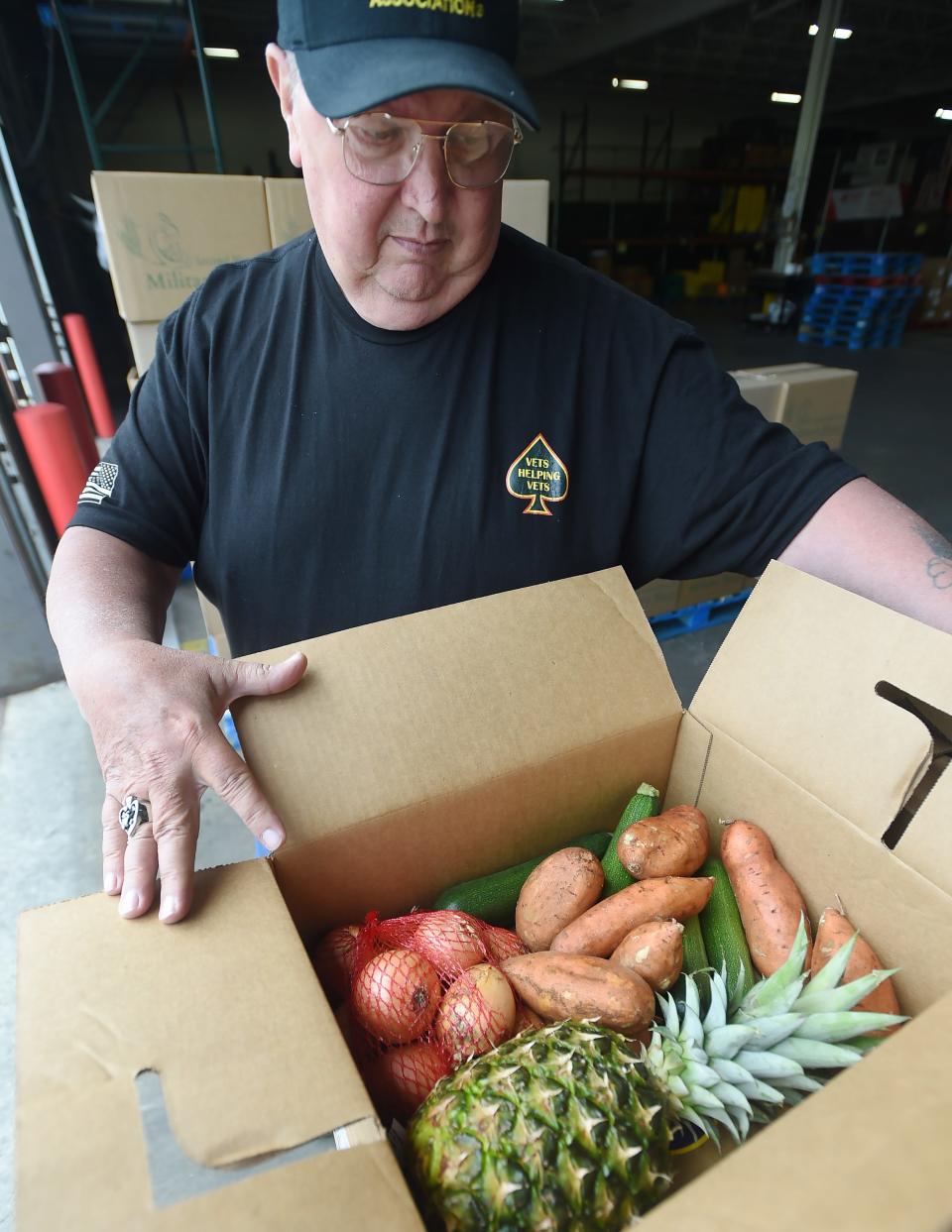 U.S. Air Force veteran Scott McCormick shows a vegetable box as part of a Military Share food distribution at the Second Harvest Food Bank in Erie in May of 2023.