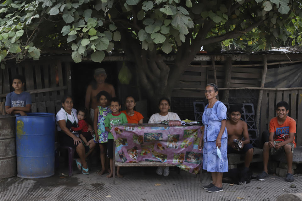 Members of the Orellana family pose for a photo outside their home in Los Angelitos, El Salvador, Wednesday, July 28, 2021. The Orellana family is among the residents of Los Angelitos who did not receive an invitation from the president to receive a new home in the residential development Ciudad Marsella. Their shack of wood pallets and aluminum sheeting held up during the October 2020 tropical storm that devastated their community, but they are awaiting the next hurricane season with fear. (AP Photo/Salvador Melendez)