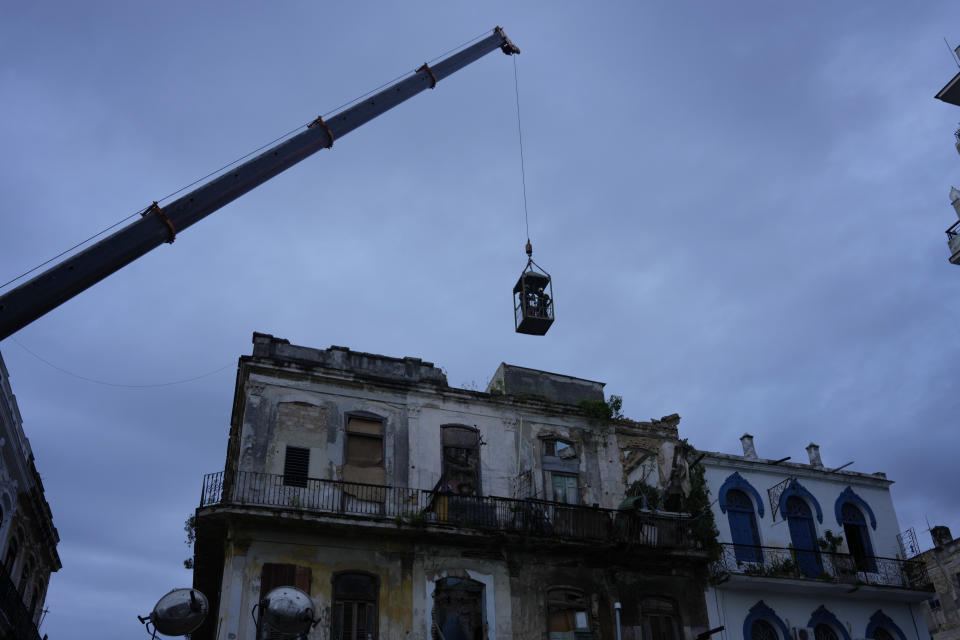 FILE - A crane lifts firefighters in a cage toward a building on Lamparilla street in search of survivors after it partially collapsed inwardly, killing three people, in Havana, Cuba, Oct. 4, 2023. The Cuban government has in the past acknowledged the problem of housing deterioration, but says the lack of material resources prevents it from tackling it. (AP Photo/Ramon Espinosa, File)
