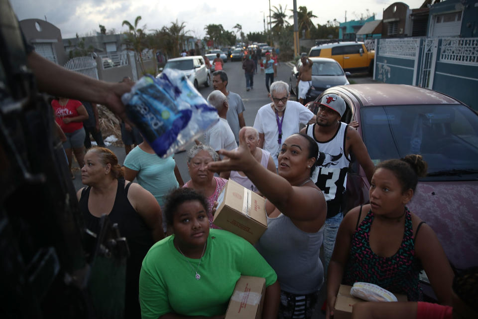 <p>Hurricane survivors receive food and water being given out by volunteers and municipal police as they deal with the aftermath of Hurricane Maria on Sept. 28, 2017 in Toa Baja, Puerto Rico. (Photo: Joe Raedle/Getty Images) </p>