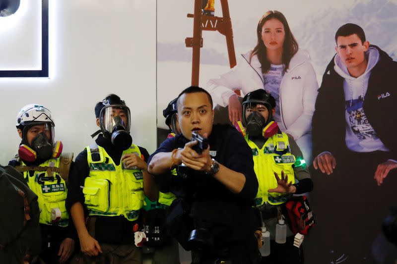 A police officer points his gun towards anti-extradition bill protesters after a clash, at Mong Kok, in Hong Kong