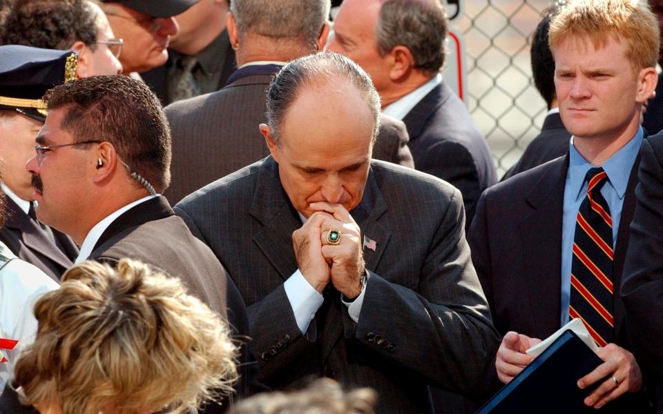 Mr Giuliani prays during a ceremony following the 9/11 attacks in New York