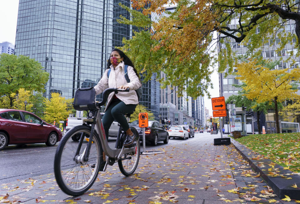A woman rides a bike in downtown Montreal, on Tuesday, Oct. 20, 2020, when the pandemic was hitting the city hard and many more people took up cycling during lockdowns. Montreal was chief among many North American cities that aggressively expanded bicycle networks in the COVID era. (Paul Chiasson/The Canadian Press via AP)