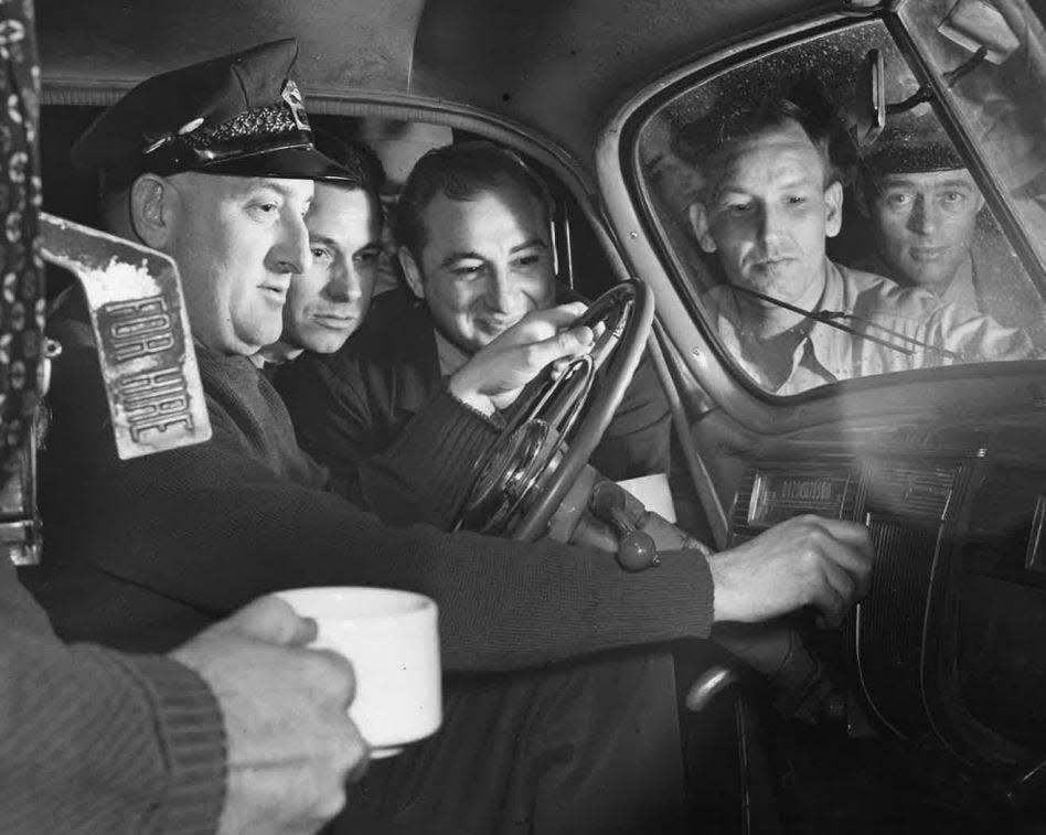 Night workers in Des Moines gather around the taxicab of Russell Wallace at 2 a.m. on June 6, 1944 to listen to reports of the D-Day invasion. Wallace had a son who had been in England since January.