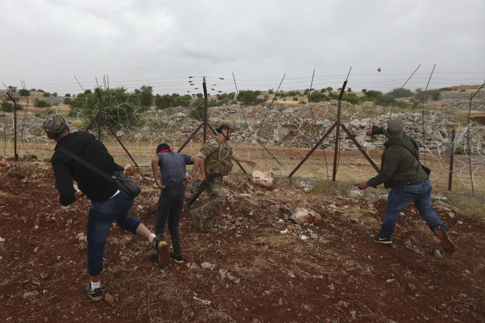 Lebanese protesters throw stones at Israeli troops on the outskirts of the southern Lebanese village of Kfar Chouba, Friday, June 9, 2023. Israeli soldiers fired tear gas to disperse scores of protesters who pelted the troops with stones along the border with Lebanon Friday, leaving some Lebanese demonstrators and troops suffering breathing problems. (AP Photo/Mohammad Zaatari)