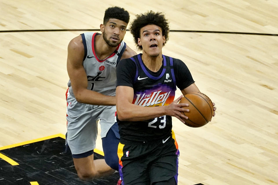 Phoenix Suns forward Cameron Johnson (23) drives past Washington Wizards forward Chandler Hutchison (1) during the first half of an NBA basketball game, Saturday, April 10, 2021, in Phoenix. (AP Photo/Matt York)