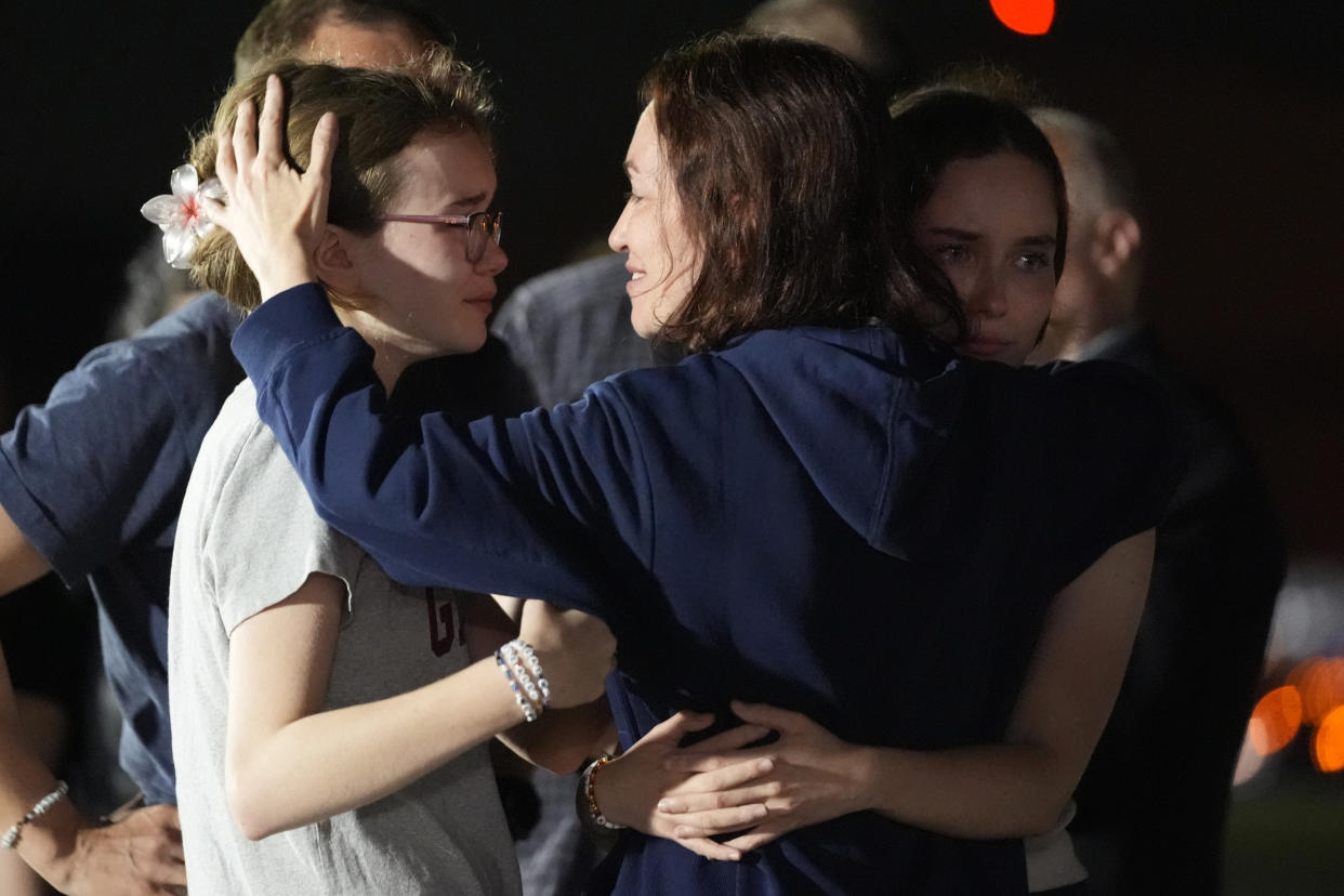 Alsu Kurmasheva hugs her daughters Miriam Butorin and Bibi Butorin as her husband Pavel Butorin stands in background at Andrews Air Force Base.