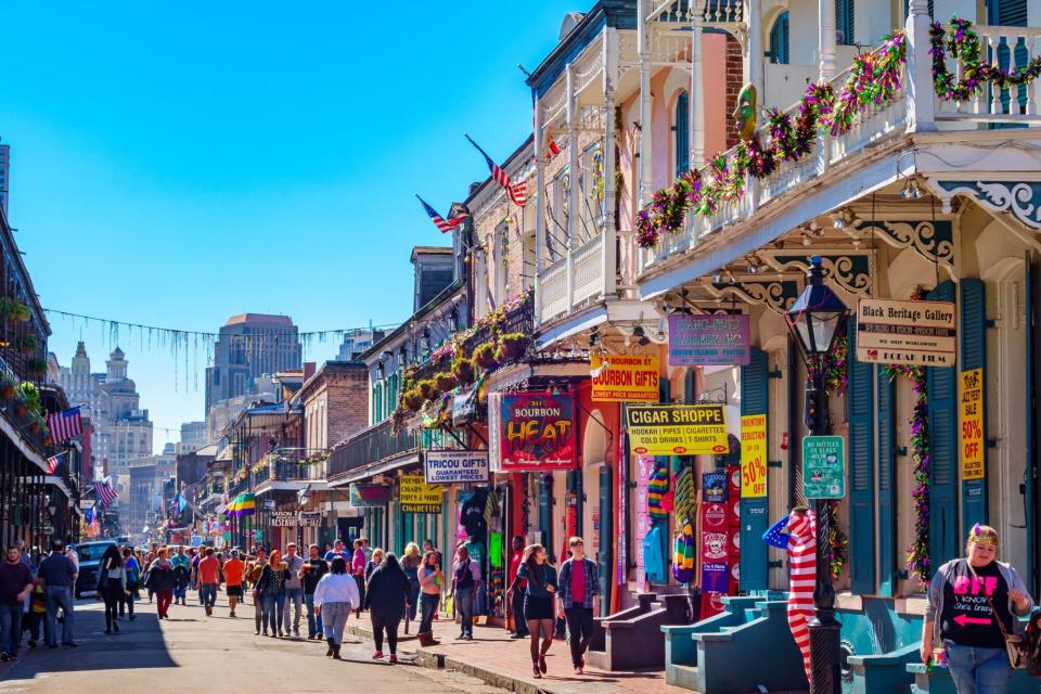 People walk on colorful Bourbon Street in the French Quarter of New Orleans during the Mardi Gras festival