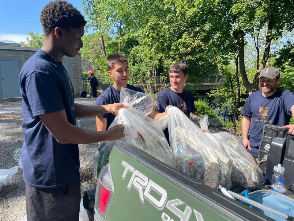 Norwich Tech freshman Carrick Byfield, seniors Navarro Dip and Michael George, and Social Studies teacher Rick Radlo place bags of trash into a truck.