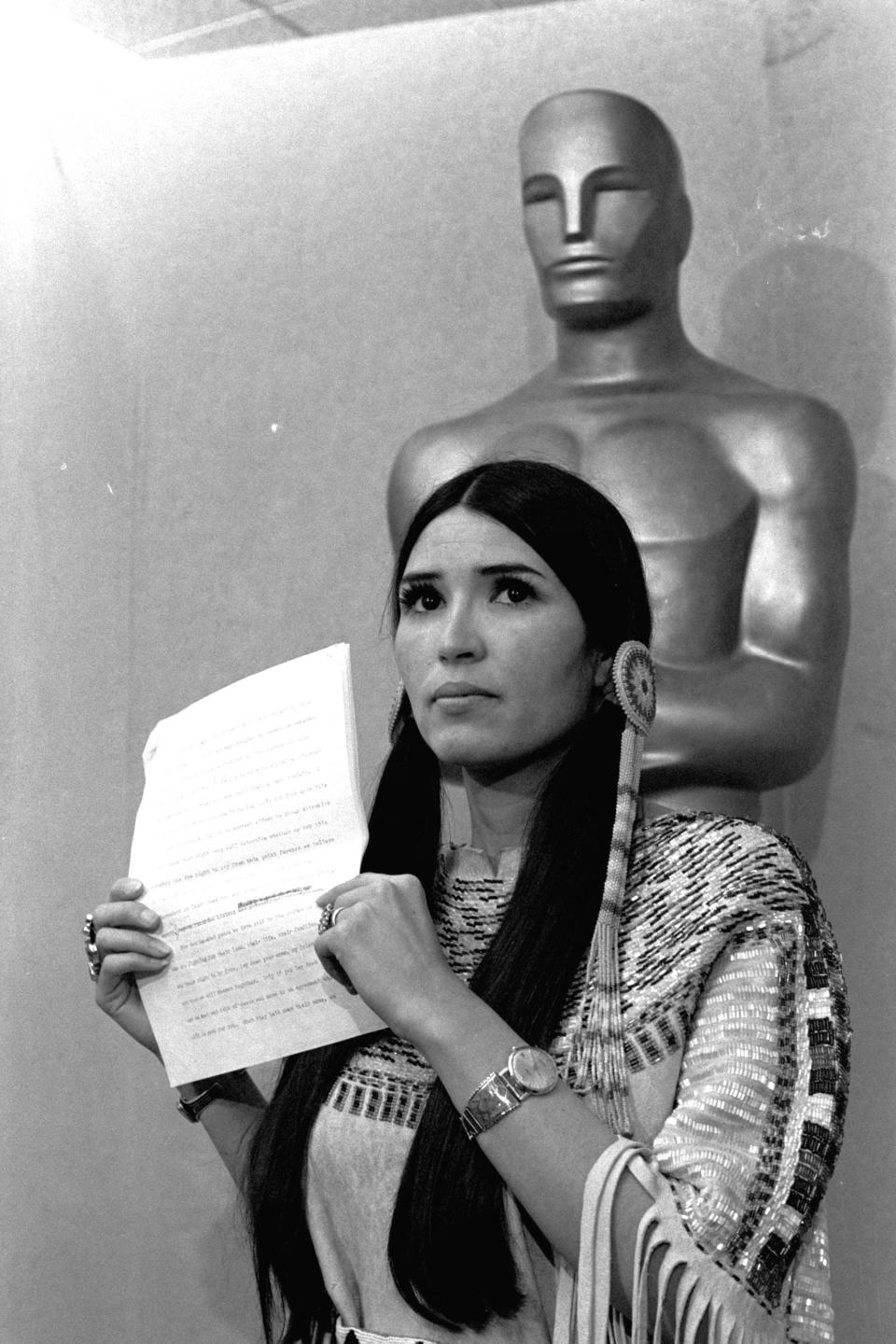 FILE - Sacheen Littlefeather, a Native American activist, tells the audience at the Academy Awards ceremony in Los Angeles, March 27, 1973, that Marlon Brando was declining to accept his Oscar as best actor for his role in "The Godfather." Sacheen Littlefeather died Sunday, Oct. 2, 2022, at her home in Marin County, Calif. She was 75. (AP Photo/File)