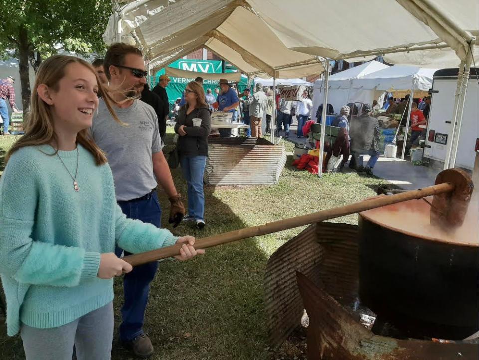 A young woman stirs apple butter at a fall festival in the Ozarks.