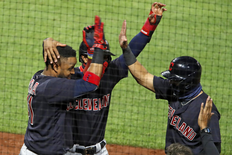 Cleveland Indians' Carlos Santana, left, celebrates with Francisco Lindor, center, and Cesar Hernandez, who were on base for his three-run home run off Pittsburgh Pirates relief pitcher Sam Howard during the tenth inning of a baseball game against the Pittsburgh Pirates in Pittsburgh, Tuesday, Aug. 18, 2020. (AP Photo/Gene J. Puskar)