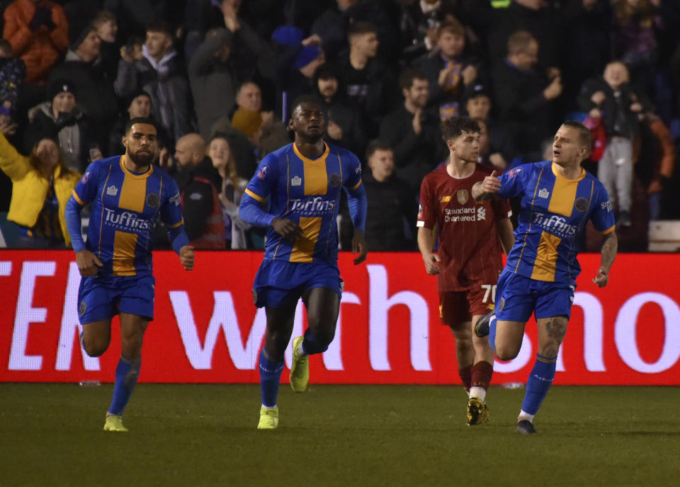 Jason Cummings, derecha, festeja con sus compañeros del Shrewsbury tras anotar el primer gol de su club en el duelo por la cuarta ronda de la Copa de la FA ante el Liverpool, en Shrewsbury, Inglaterra, el domingo 26 de enero de 2020. (AP Foto/Rui Vieira)