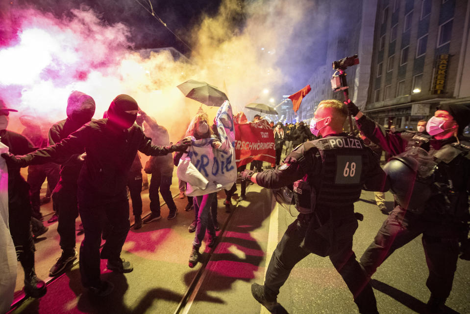 Demonstrators take part in a rally against the curfews and ignite pyrotechnics, in Frankfurt/Main, Germany, Saturday, April 24, 2021. Accompanied by the police, the participants of the rally moved through the city center. On Saturday, the regulation of a federal coronavirus restriction is in effect, that includes, among other things, curfew restrictions between 10 p.m. and 5 a.m. (Boris Roessler/dpa via AP)