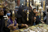 Women ignore social distancing and some do not wear face masks as they shop for the upcoming Eid al-Fitr holiday that marks the end of the Muslim holy fasting month of Ramadan after the government announced new restrictions, in Karachi, Pakistan, Wednesday, May 5, 2021. Pakistani authorities plan to put in place a nine-day lockdown from May 8 to 16 prior to the holiday. (AP Photo/Fareed Khan)