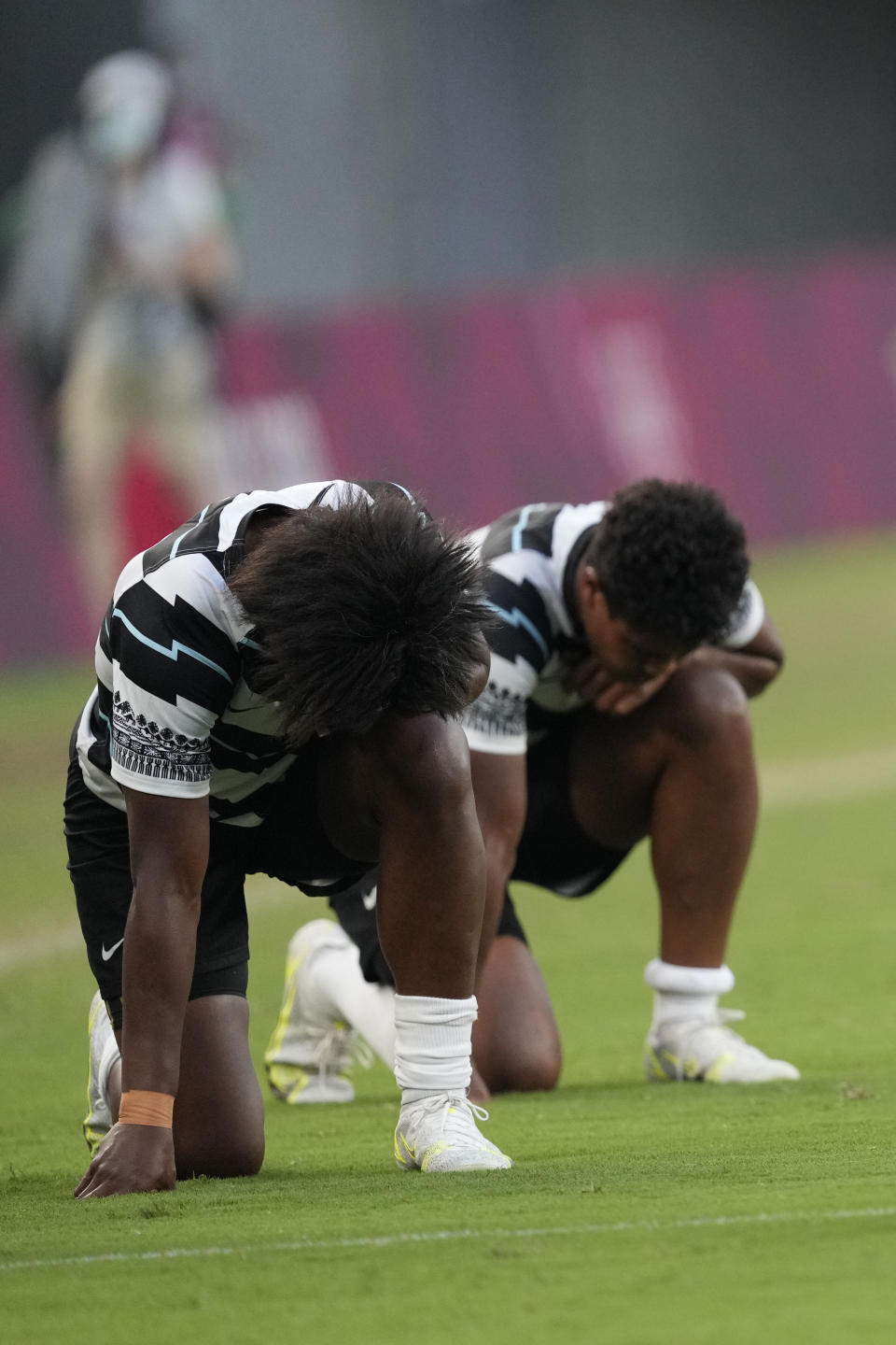 Fiji players kneel on the pitch after defeating Britain in the women's rugby bronze medal match at the 2020 Summer Olympics, Saturday, July 31, 2021 in Tokyo, Japan. (AP Photo/Shuji Kajiyama)