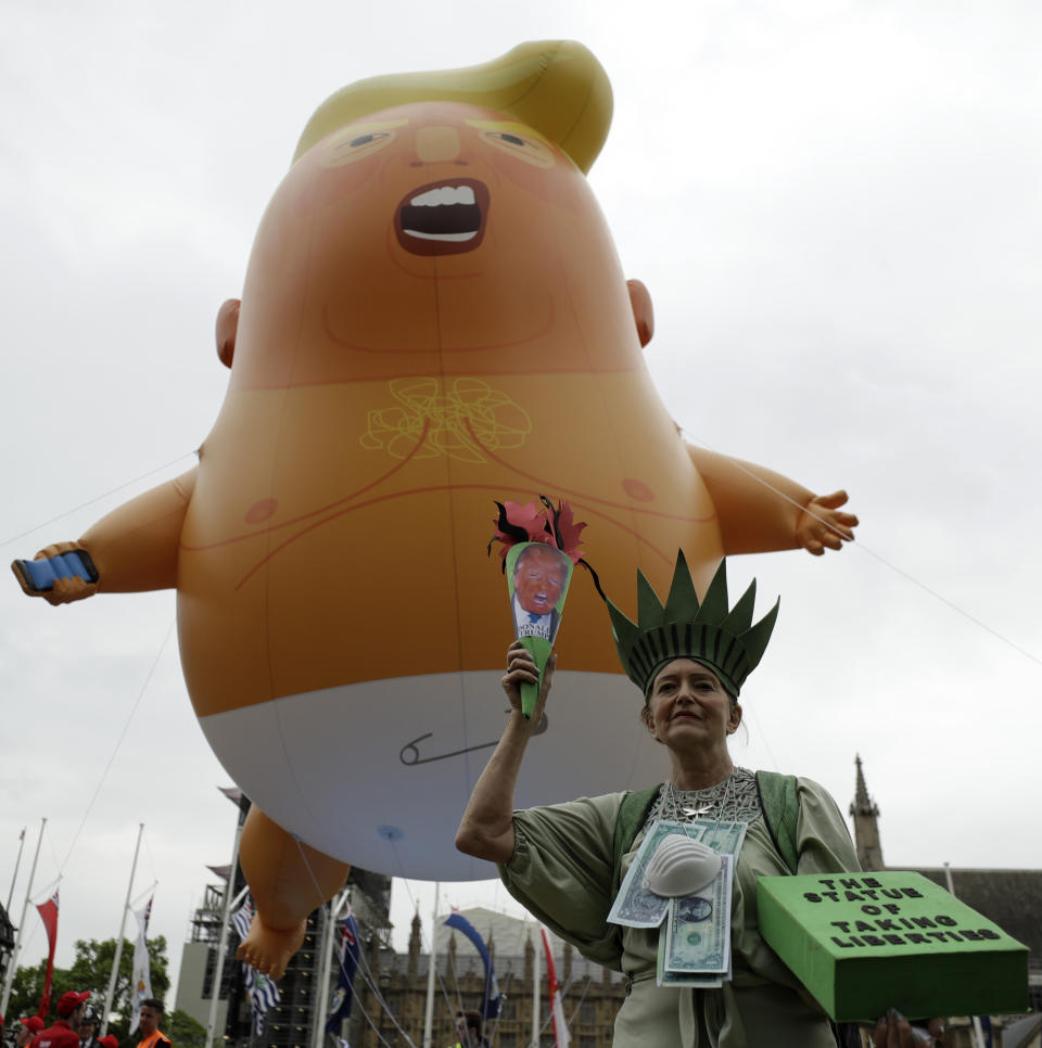 A woman posing as statue of liberty stands next to the 'Trump Baby' blimp as people gather to demonstrate against the state visit of President Donald Trump in Parliament Square, central London, Tuesday, June 4, 2019. Trump will turn from pageantry to policy Tuesday as he joins British Prime Minister Theresa May for a day of talks likely to highlight fresh uncertainty in the allies' storied relationship. (AP Photo/Matt Dunham)