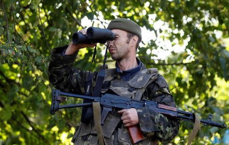 A Ukrainian serviceman uses a pair of binoculars to look at pro-Russian rebel positions near Donetsk, September 16, 2014. REUTERS/David Mdzinarishvili