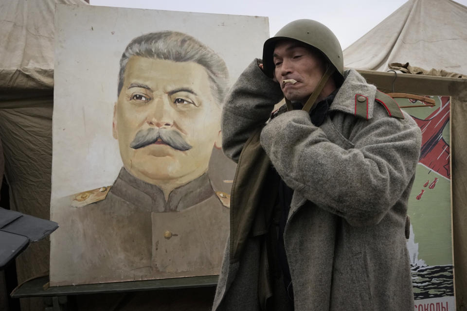 A man wears World War II ages Soviet Army's uniform near a portrait of Soviet dictator Josef Stalin at a military-historical exhibition at the Dvortsovaya (Palace) Square, in St. Petersburg, Russia, Saturday, Jan. 27, 2024. The exhibition marked the 80th anniversary of the battle that lifted the Siege of Leningrad. The Nazi siege of Leningrad, now named St. Petersburg, was fully lifted by the Red Army on Jan. 27, 1944. More than 1 million people died mainly from starvation during the nearly900-day siege. (AP Photo/Dmitri Lovetsky)