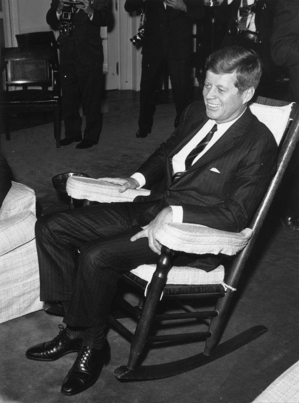 John F. Kennedy poses for photographers in his favorite rocking chair in the White House in 1963.