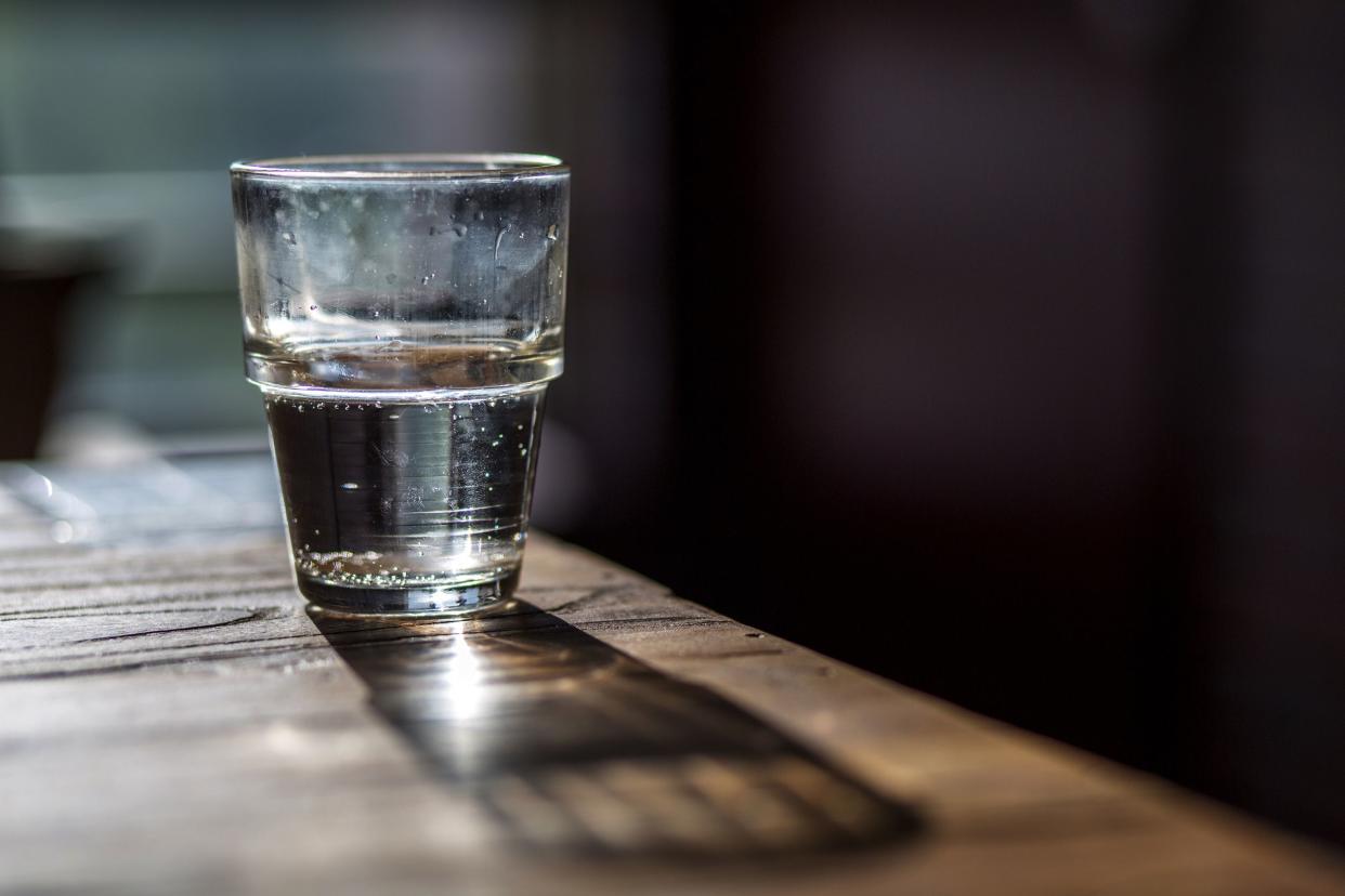 lone water glass on wooden table at bar