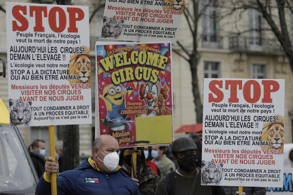 Circus workers holds posters during a protest near the National Assembly, Tuesday, Jan.26, 2021. French lawmakers start debating Tuesday a bill that would ban using wild animals in traveling circuses and keeping dolphins and whales in captivity in marine parks, amid other measures to better protect animal welfare. Circus workers stage a protest outside the National Assembly to denounce what they consider "a mistake." (AP Photo/Lewis Joly)