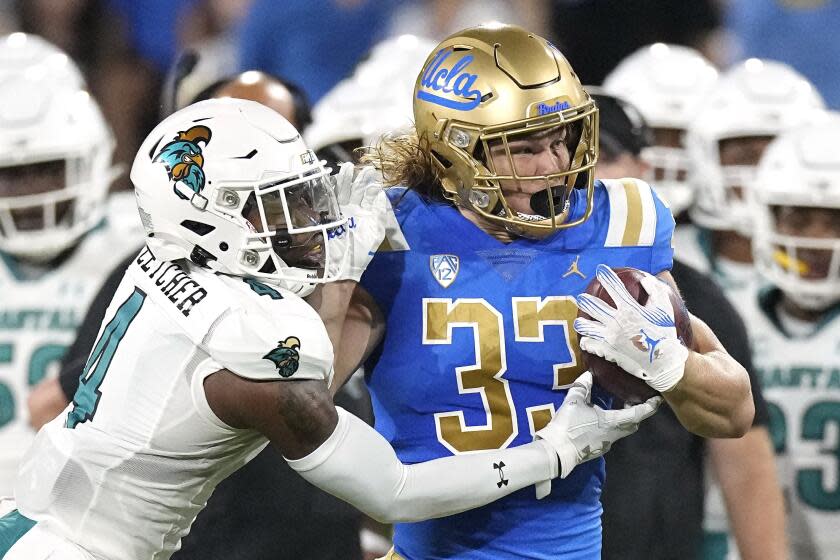 UCLA running back Carson Steele, right, fends off Coastal Carolina safety Tobias Fletcher.