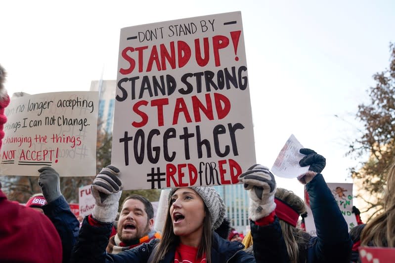 Paige Abdon, a 3rd grade teacher with the Lafayette School Corperation, lifts a sign as teachers hold a one day walkout at the statehouse in Indianapolis