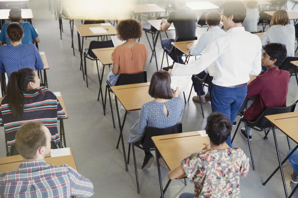 People sitting at desks in a classroom as a person walks down the aisle