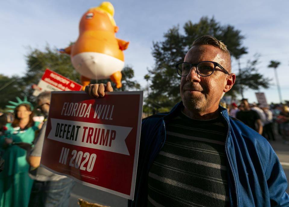 Dennis Becker, 54, from Fort Lauderdale, gathers near the BB&T Center with a giant inflatable baby of President Donald Trump before a "homecoming" rally in Sunrise, Florida on Tuesday, Nov. 26, 2019. The rally is being held in celebration of Donald Trump's decision to change his full-time residence from Manhattan to Palm Beach. (Matias J. Ocner/Miami Herald via AP)