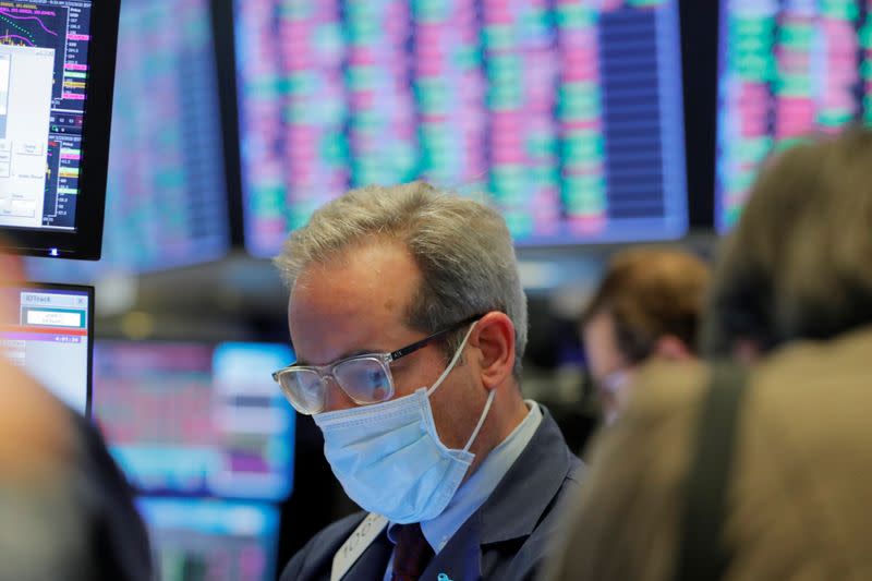 A trader wears a mask as he works on the floor of the New York Stock Exchange (NYSE) as the building prepares to close indefinitely due to the coronavirus disease (COVID-19) outbreak in New York