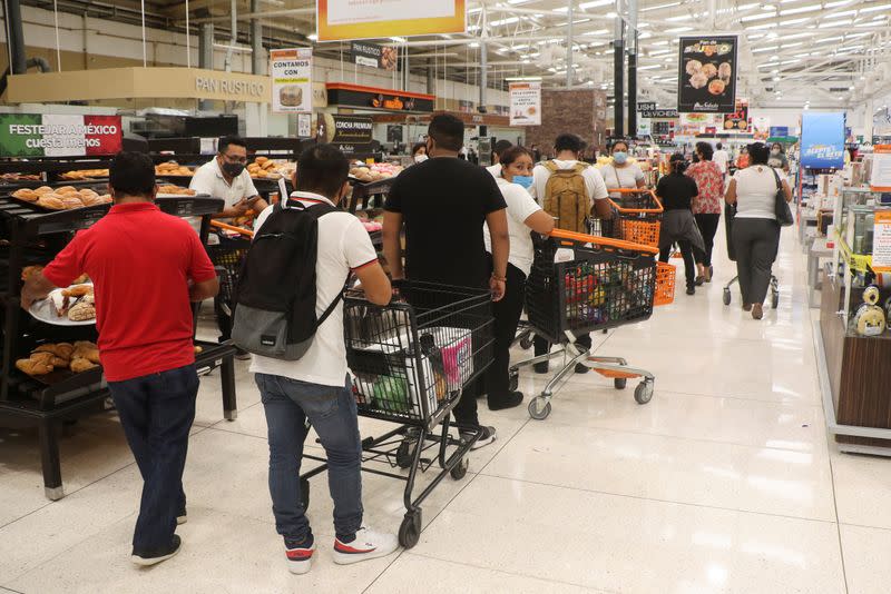 People queue to pay for goods at a supermarket, in preparation for the arrival of Hurricane Delta, in Cancun