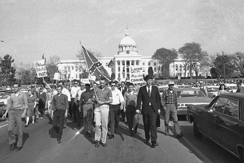 FILE - A white group, the Organization for Better Government, carries a Confederate flag as they march away from the capitol in Montgomery, Ala., March 18, 1965. They halted within 25 feet of racial pickets, had several speeches then marched off again. (AP Photo/File)