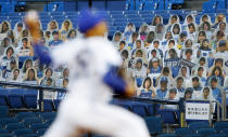 Spectators' seats are covered with large panels, carrying faces of fans with messages during an opening baseball game between the Yokohama Baystars and the Hiroshima Toyo Carp at a stadium in Yokohama, near Tokyo, Friday, June 19, 2020. After a three-month delay caused by the coronavirus pandemic, the world's second-most famous baseball league opened a shortened season Friday without the presence of fans. (Kyodo News via AP)