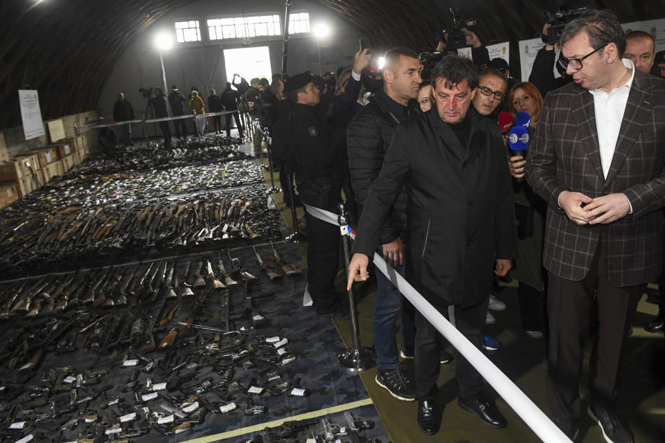 In this photo provided by the Serbian Presidential Press Service, Serbian President Aleksandar Vucic, right, inspects weapons collected as part of an amnesty near the city of Smederevo, Serbia, Sunday, May 14, 2023. Serbian authorities on Sunday displayed some of around 13,500 weapons they say have been collected since last week's mass shootings, including automatic weapons, hand bombs and anti-tank grenades. (Serbian Presidential Press Service via AP)