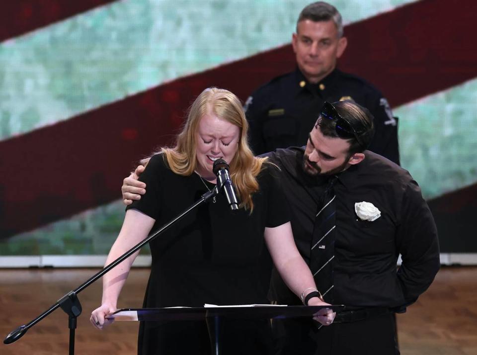 Ashley Eyer, left, wife of fallen Charlotte-Mecklenburg Police Officer Joshua Eyer, speaks during her husband’s funeral at First Baptist Church in Charlotte, NC on Friday, May 3, 2024. At right, Joshua Eyer’s best friend Charlie Sardelli offers support. Mourners gathered at First Baptist Church to honor slain Charlotte-Mecklenburg Police Officer Joshua Eyer who died from wounds sustained during a standoff with a gunman on Monday, April 29th.