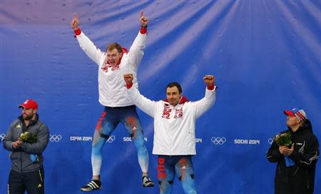 Russia's Alexander Zubkov (2nd L) and Alexey Voevoda (2nd R) celebrate on the podium at the flower ceremony between Switzerland's Alex Baumann (L) and Steven Holcomb of the U.S. after winning the two-man bobsleigh event at the 2014 Sochi Winter Olympics, at the Sanki Sliding Center in Rosa Khutor February 17, 2014. REUTERS/Arnd Wiegmann