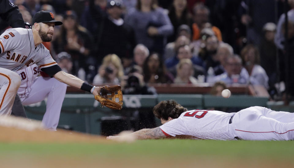 Boston Red Sox's Sam Travis, right, dives to third base for a triple as San Francisco Giants' Evan Longoria, left, tries to field the ball during the sixth inning of a baseball game at Fenway Park in Boston, Tuesday, Sept. 17, 2019. Travis left the game after the play. (AP Photo/Charles Krupa)