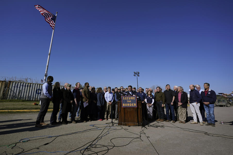 U.S. House Speaker Mike Johnson, center, stands with more than 60 fellow Republicans in Congress as he talks to the media during a visit to the U.S.- Mexico border, Wednesday, Jan. 3, 2024, in Eagle Pass, Texas. According to U.S. officials, a Mexican enforcement surge has contributed to a sharp drop in illegal entries to the U.S. in recent weeks. (AP Photo/Eric Gay)