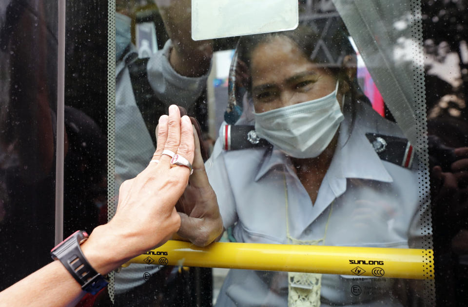 A pro-democracy protester, partly seen at left, and a bus ticket clerk, right, gesture three-fingered flash each other, in Bangkok, Thailand, Sunday, Oct. 25, 2020. Pro-democracy protesters in Thailand gathered again Sunday in Bangkok, seeking to keep up pressure on the government a day ahead of a special session of Parliament called to try to ease political tensions. (AP Photo/Sakchai Lalit)