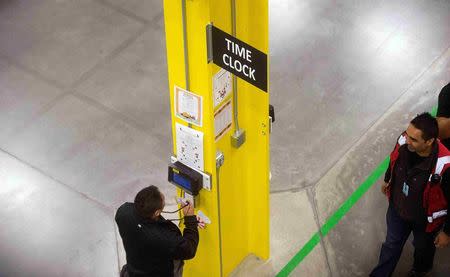 Workers use a time clock at an Amazon Fulfillment Center, ahead of the Christmas rush, in Tracy, California, November 30, 2014. REUTERS/Noah Berger